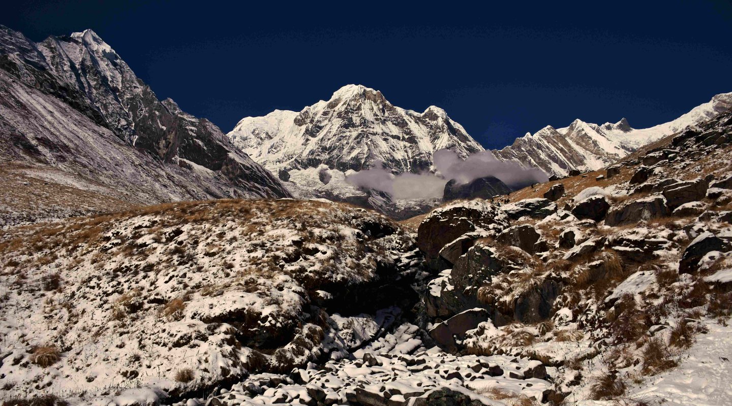 Close-up of sharp Himalayan peaks draped in snow above the Annapurna Sanctuary, under deep blue skies, capturing the rugged alpine terrain.