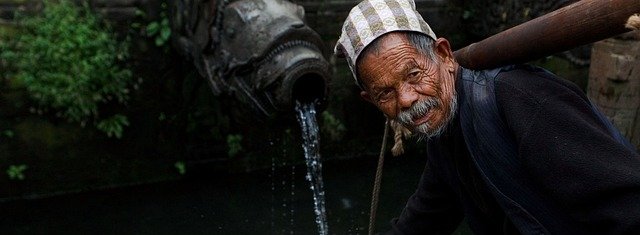 an-ond-man-collecting-water-from-a-traditional-tap-in-nepal