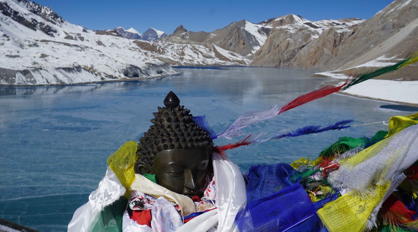 Colorful Tibetan prayer flags fluttering next to a serene Buddha statue in the Himalayas