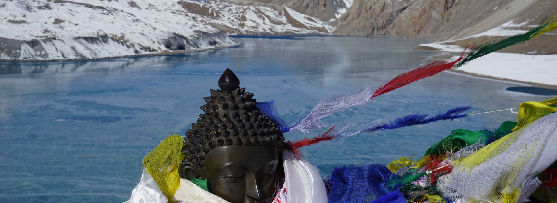 Colorful Tibetan prayer flags fluttering next to a serene Buddha statue in the Himalayas