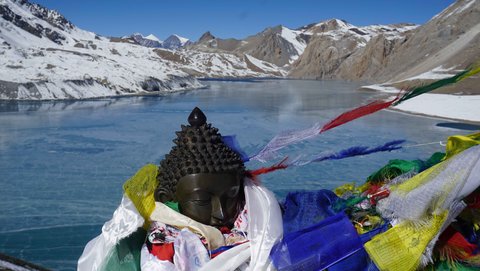 Colorful Tibetan prayer flags fluttering next to a serene Buddha statue in the Himalayas