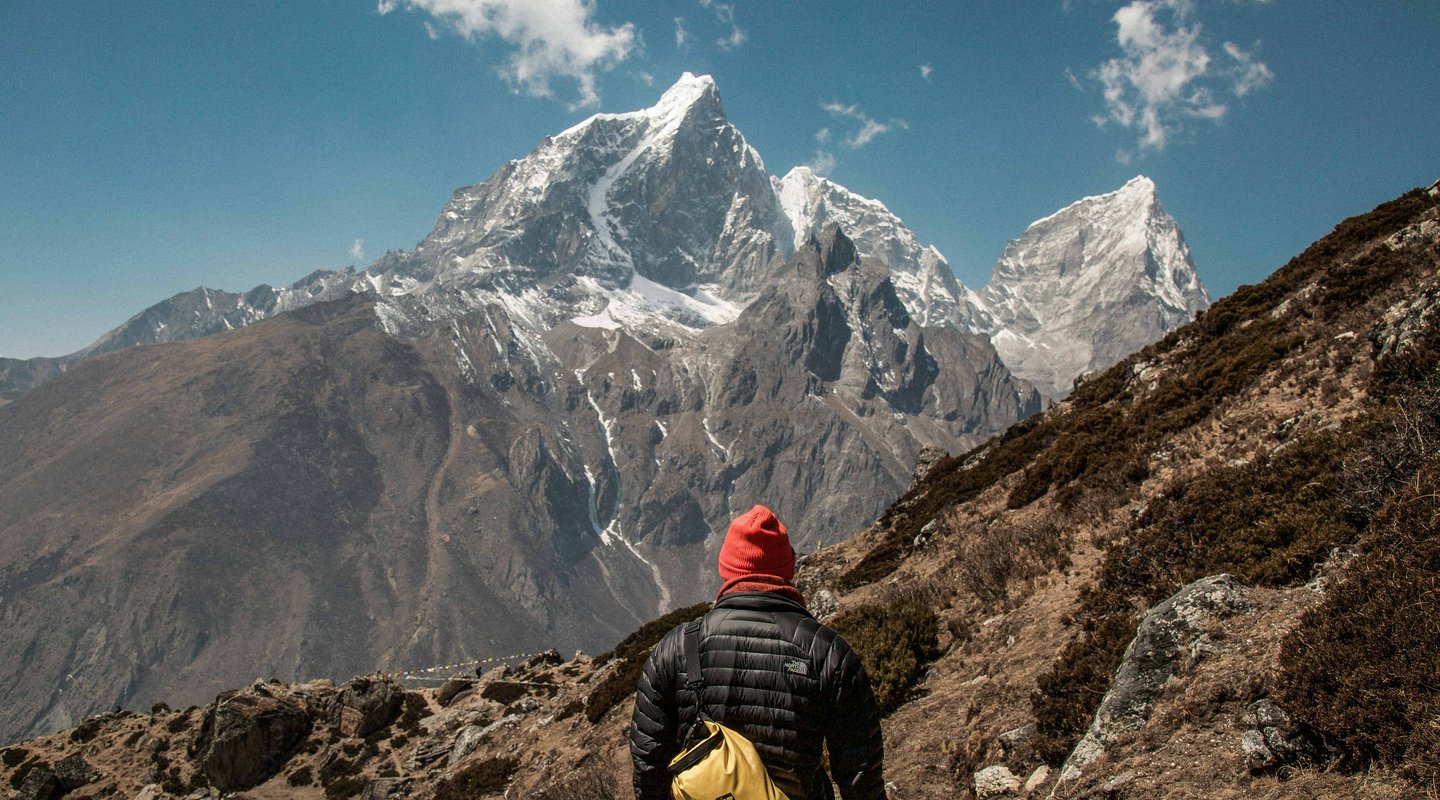 “Trekker walking on the Everest Three Pass trek trail with panoramic Himalayan mountain views in Nepal.”