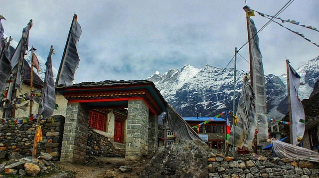 Traditional stone houses and prayer flags at Kyanjin Gompa village in Langtang Valley with dramatic Himalayan mountains behind