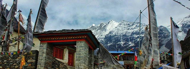 Traditional stone houses and prayer flags at Kyanjin Gompa village in Langtang Valley with dramatic Himalayan mountains behind