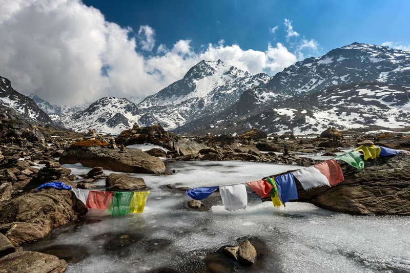 "Prayer flags fluttering along rocky Langtang Valley trekking path"