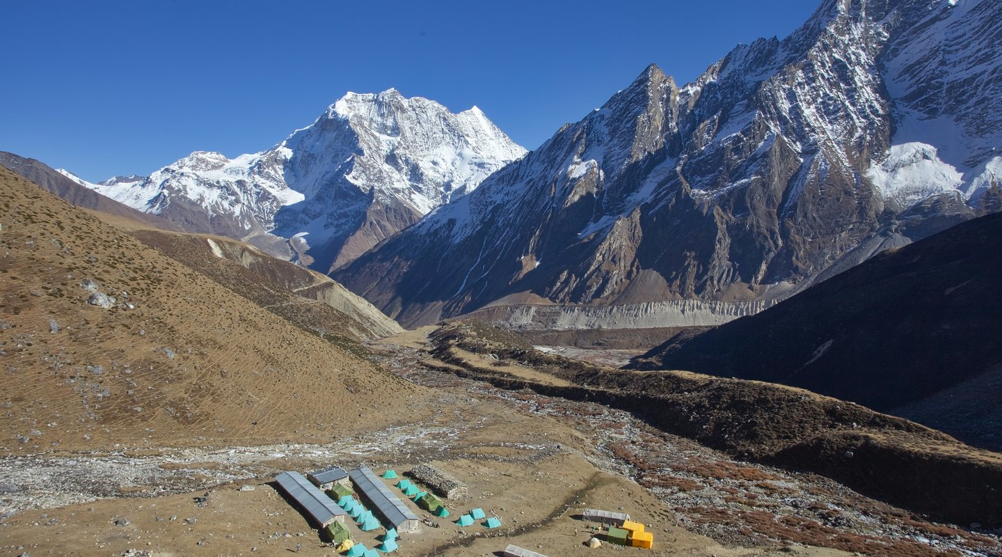 Traditional stone houses of a Nepalese village along the Manaslu Circuit route with mountains behind.