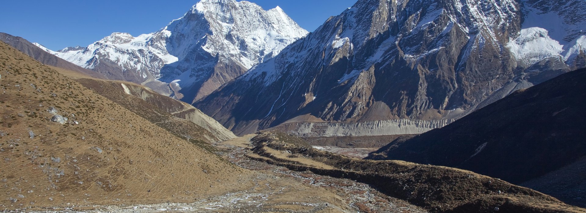 Traditional stone houses of a Nepalese village along the Manaslu Circuit route with mountains behind.