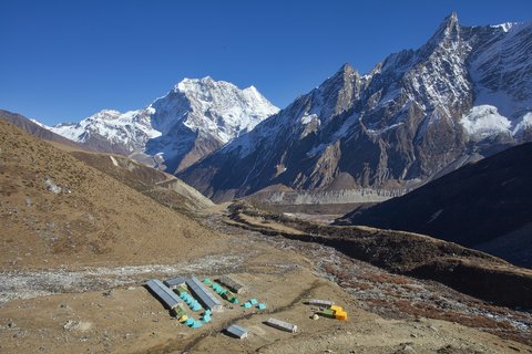Traditional stone houses of a Nepalese village along the Manaslu Circuit route with mountains behind.
