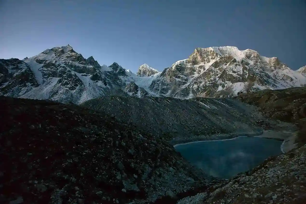 Manaslu Circuit Trek view with a pristine alpine lake in the foreground and towering Himalayan peaks in the background, Nepal.