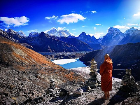 Buddhist monk overlooking Gokyo Lakes with panoramic view of Mount Everest and Himalayan peaks in Nepal