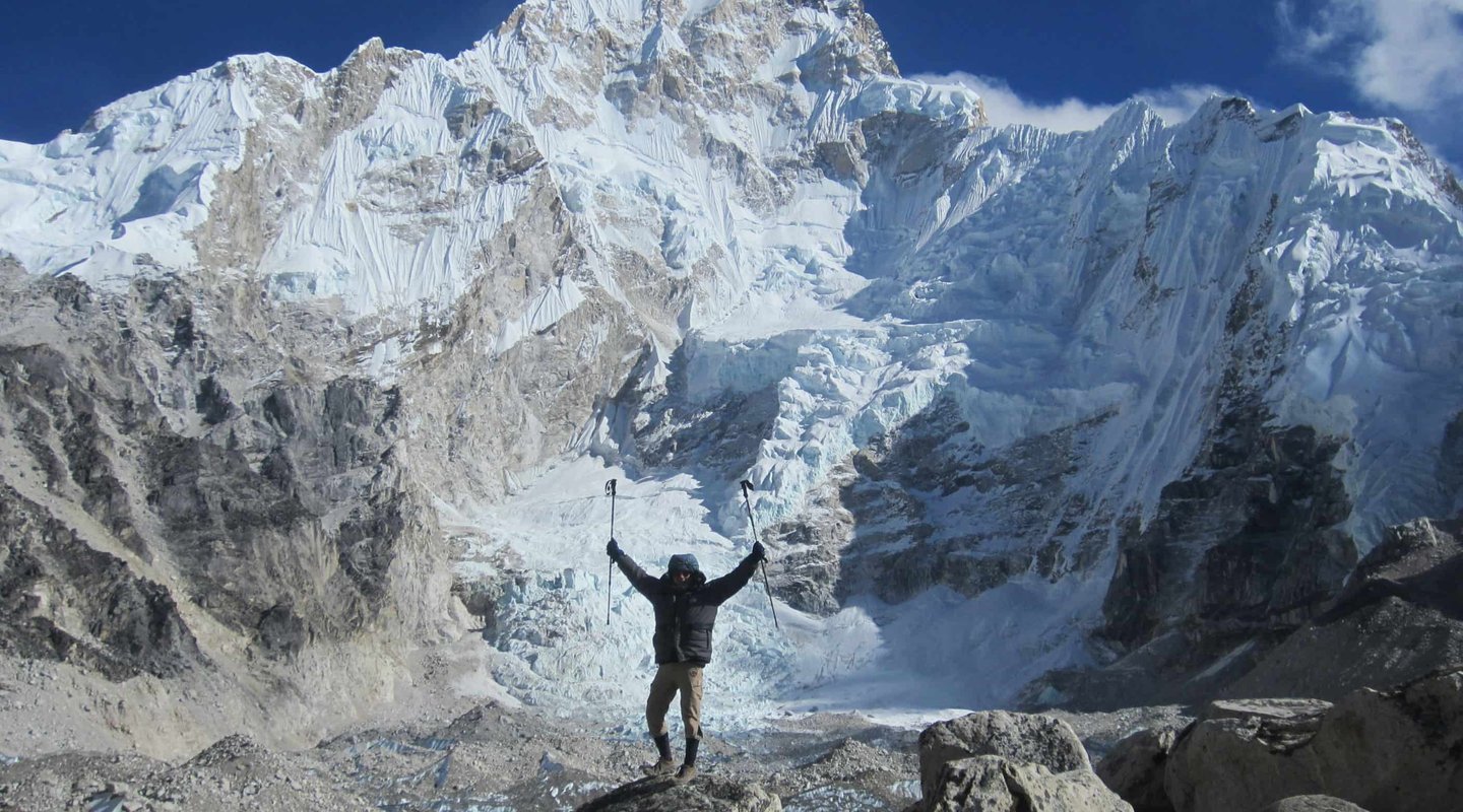 Trekkers celebrating at the base of Mount Everest with stunning snow-covered Himalayan peaks and glaciers during Everest Base Camp trek in Nepal.