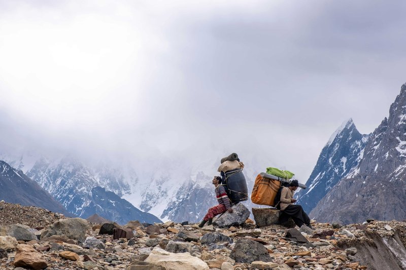 epalese porters carrying heavy loads resting on rocks with misty Annapurna range views during ABC trek Nepal