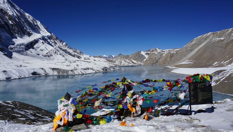 Peaceful Himalayan scene with prayer flags and a golden Buddha statue during sunset