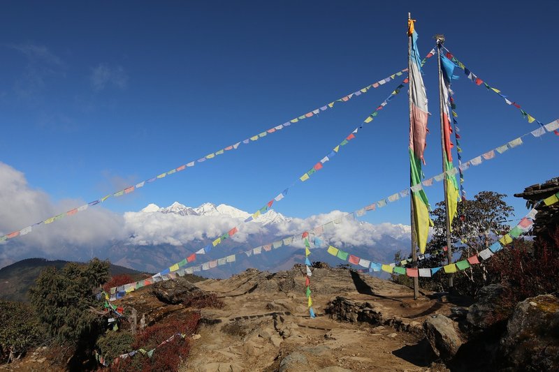"Colorful prayer flags fluttering against a backdrop of snow-capped Himalayan mountains in Langtang."