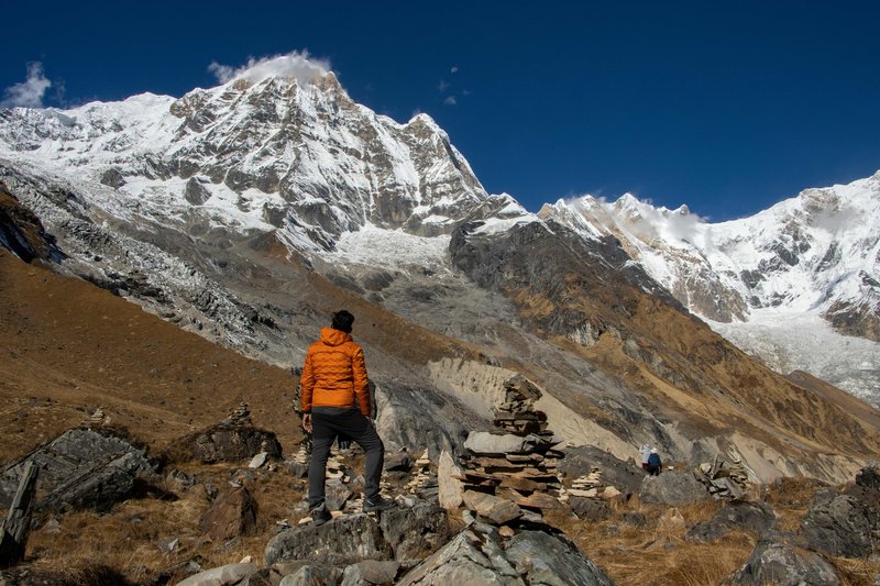 Focused trekker in hiking boots carefully stepping across loose rocks on challenging mountain path
