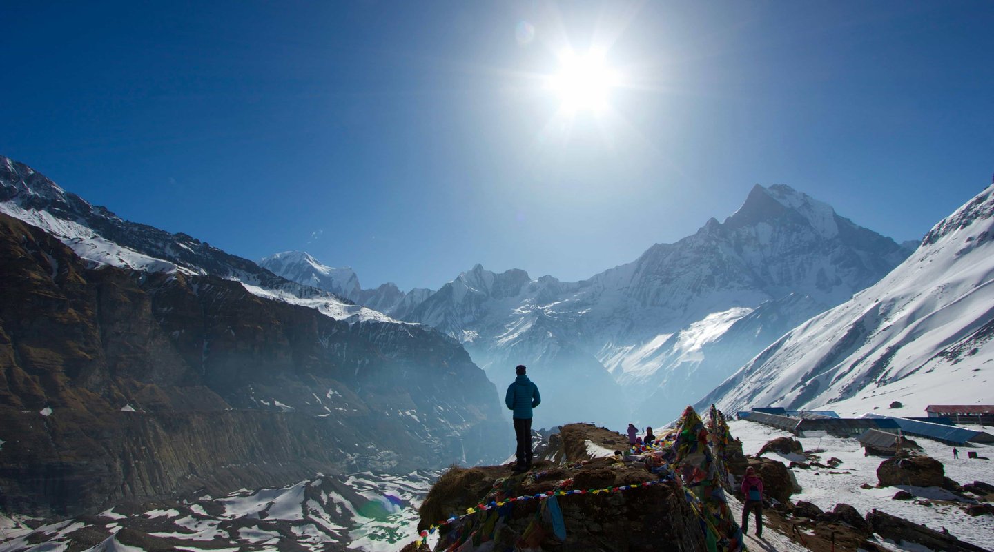 Solo trekker on mountain trail with Machapuchare (Fishtail) peak visible in distance