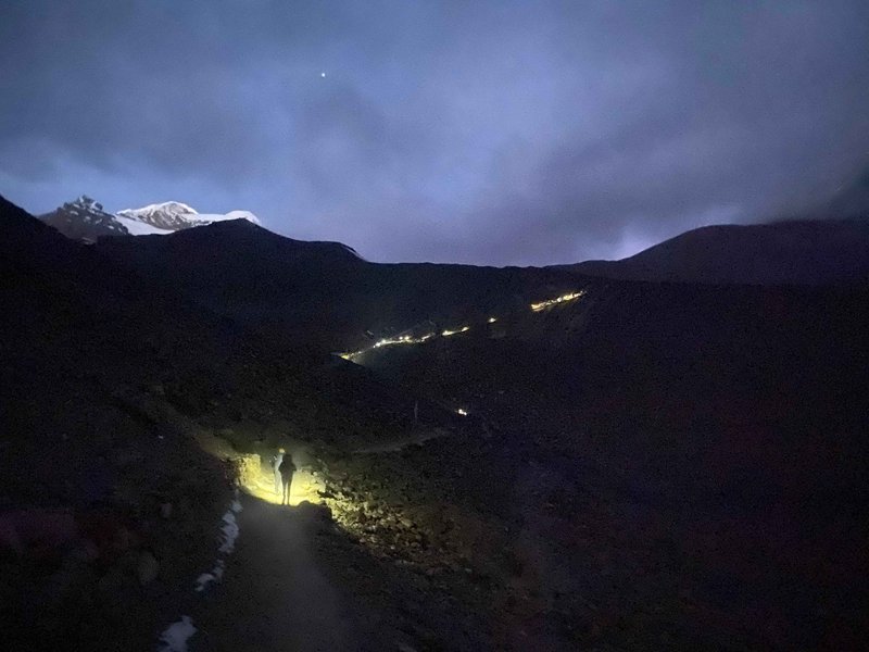 Trekkers using headlamps while night hiking on Annapurna Circuit trail under starry Himalayan sky