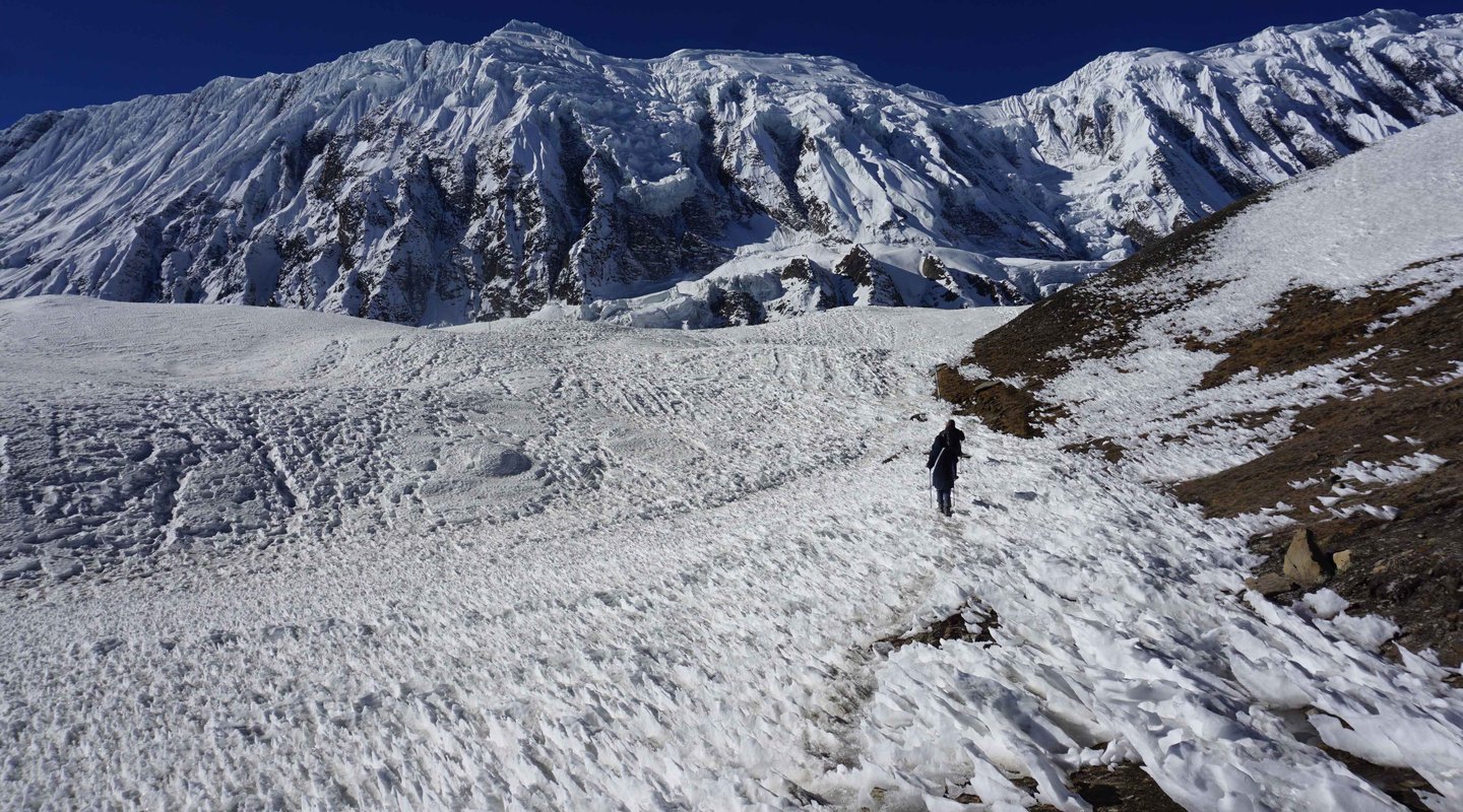 Trekkers crossing icy terrain on Annapurna Circuit trek in Nepal Himalayas during winter season