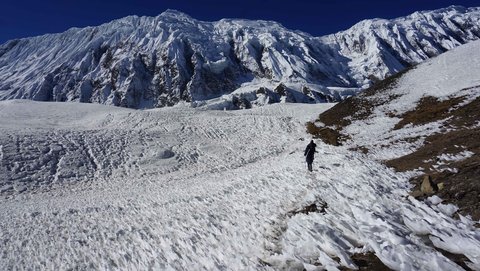 Trekkers crossing icy terrain on Annapurna Circuit trek in Nepal Himalayas during winter season