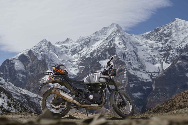 Himalayan Royal Enfield motorcycle parked against stunning mountain backdrop during Upper Mustang motorbike tour in Nepal