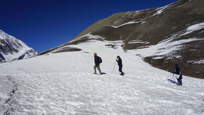 Trekkers hiking through the icy trails of the Annapurna Circuit under a clear blue sky