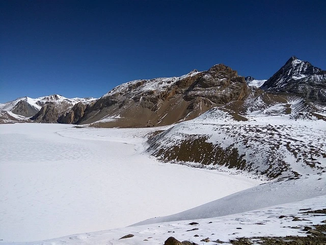 Icy turquoise surface of frozen Tilicho Lake on the Annapurna Circuit route in winter.