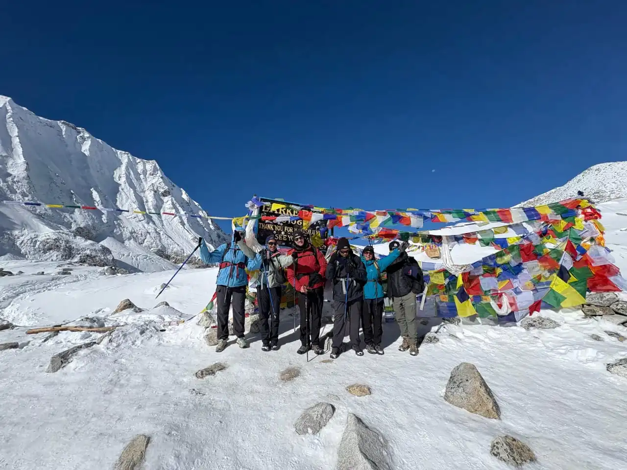 Trekkers standing at the Larke Pass summit on the Short Manaslu Circuit Trek, overlooking panoramic snow-capped peaks.