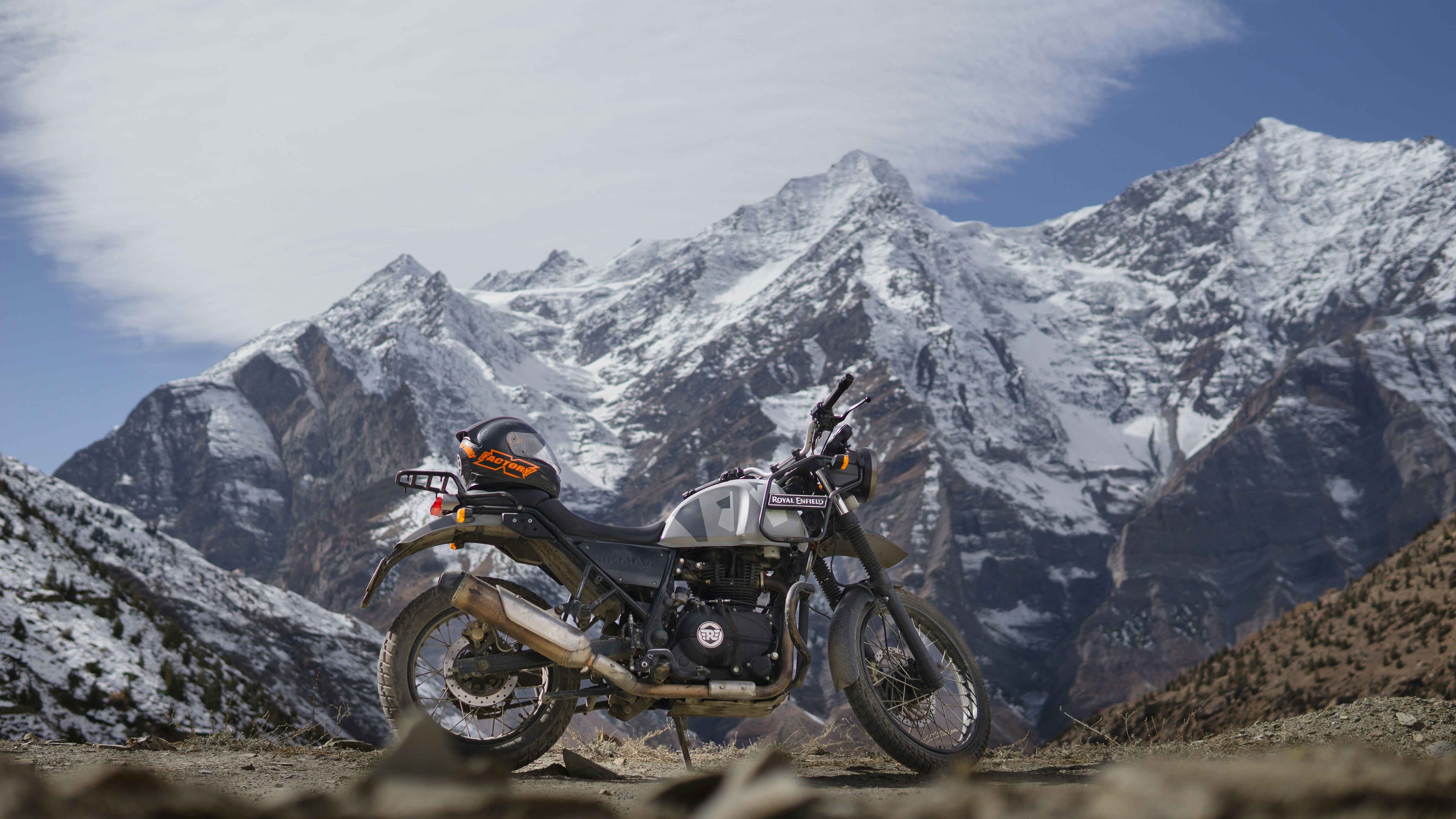 Himalayan Royal Enfield motorcycle parked against stunning mountain backdrop during Upper Mustang motorbike tour in Nepal